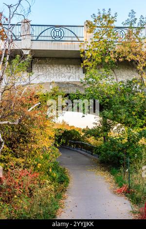 Eine Brücke mit einem Pfad darunter. Der Pfad ist von Bäumen gesäumt, und die Blätter ändern ihre Farbe Stockfoto