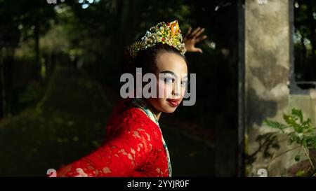 Eine traditionelle indonesische Tänzerin bezaubert mit ihrem wunderschönen Aussehen und trägt ein rotes Kostüm, das das Auge des Publikums im Wald i erregt Stockfoto