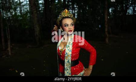 Eine traditionelle indonesische Tänzerin bezaubert mit ihrem wunderschönen Aussehen und trägt ein rotes Kostüm, das das Auge des Publikums im Wald i erregt Stockfoto