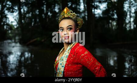 Eine traditionelle indonesische Tänzerin bezaubert mit ihrem wunderschönen Aussehen und trägt ein rotes Kostüm, das das Auge des Publikums im Wald i erregt Stockfoto