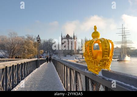 Goldene Krone Ornament auf der skeppsholmsbron Brücke zur Insel skeppsholmen im Zentrum von Stockholm, Schweden im Winter mit Schnee auf dem Boden an einem sonnigen Tag Stockfoto