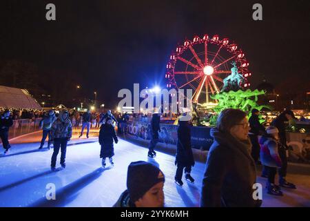 Schlittschuhläufer vor dem Neptunbrunnen und einem Riesenrad auf dem Weihnachtsmarkt am Alexanderplatz, Berlin, 21.12.2024 Stockfoto