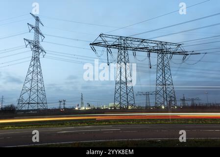 Hochspannungsmasten neben einer Straße mit leichten Spuren vorbeifahrender Autos in der Dämmerung, Wolmirstedt, Sachsen-Anhalt, Deutschland, Europa Stockfoto