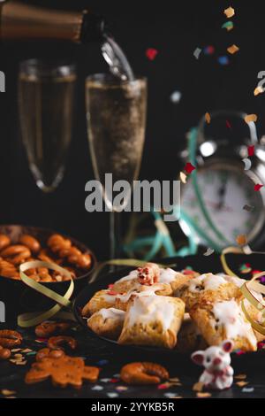 Silvester, Gebäck und Sektgläser auf einem Tisch, Champagner gießen Stockfoto