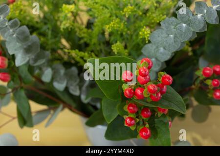 Ein Blick aus der Nähe auf einen wunderschönen Blumenstrauß im Weihnachtsstil mit hypericum-Beeren und Eukalyptusblättern. Stockfoto