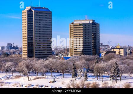 Eine Skyline der Stadt mit zwei hohen Gebäuden und einem Park im Vordergrund. Die Gebäude sind mit Schnee bedeckt, was der Szene eine ruhige und friedliche Atmosphäre verleiht Stockfoto