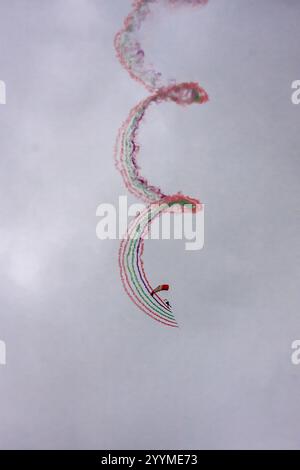 Eine bunte Spirale aus Rauchspuren am Himmel. Ein Mann fliegt einen Drachen mitten in der Spirale Stockfoto