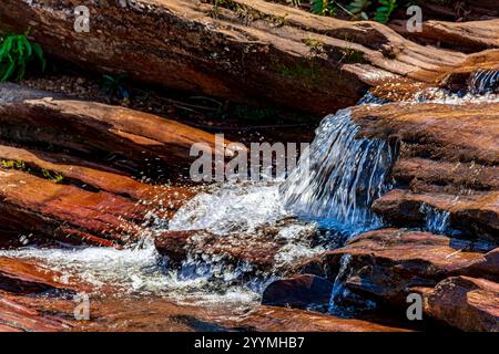 Wasser fließt über die Felsen und bildet eine kleine Kaskade Stockfoto