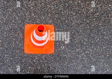 Verkehrskegel, weiße und orangene Streifen auf grauem Asphalt, Kopierraum. Baukegel markieren einen Teil der Straße mit einer Schicht frischen Asphalts. Stockfoto