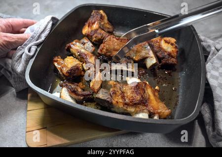 Braten von Kalb- und Rindfleisch mit viel ausgeschmolzenem Fett in einer Ofenpfanne, Zubereitung für das Kochen eines Demi-Glace oder einer braunen Sauce in der französischen Küche, Auswahl Stockfoto