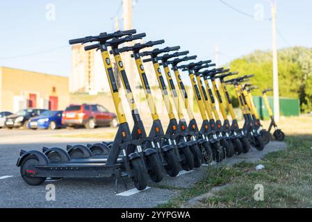 Verleih von Elektrorollern. Leuchtend gelbe Elektroroller zum Verleih stehen im Stadtpark. Gelbe elektrische Kick-Sharing-Roller. Russland, Tscheboksary. 7 Stockfoto