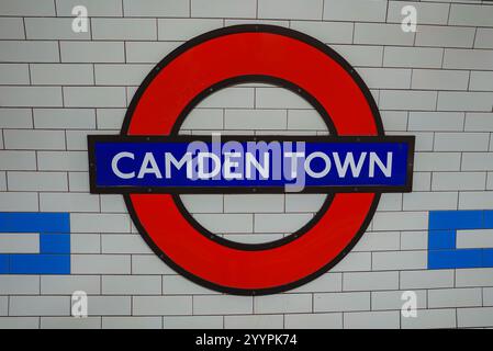 Das berühmte Rundschild für den Bahnhof Camden Town steht vor weißen Ziegelwänden und zeigt ein Schlüsselsymbol für Londons öffentliches Verkehrssystem. Stockfoto