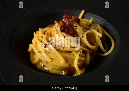 Spaghetti Carbonara italienische Pasta im römischen Stil mit Ei- und Käsesoße, garniert mit Guanciale-Speck Stockfoto