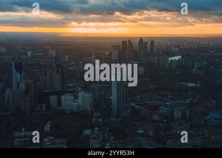 Blick aus der Luft auf London bei Sonnenuntergang mit modernen Wolkenkratzern, einschließlich The Shard, unter einem Himmel aus Orange und Gelb, der ein warmes Stadtlicht ausstrahlt. Stockfoto