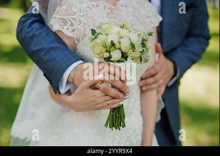 Intimer Moment eines Brautpaares, das Bouquet in der Natur hält. Stockfoto