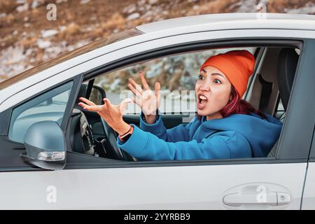 Eine junge Frau, die Auto fährt, zeigt Wut auf der Straße, schreiend und zornig Stockfoto