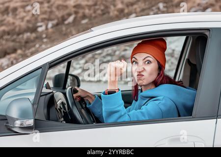 Eine wütende Fahrerin schüttelt während der Fahrt mit der Faust auf ein anderes Auto Stockfoto