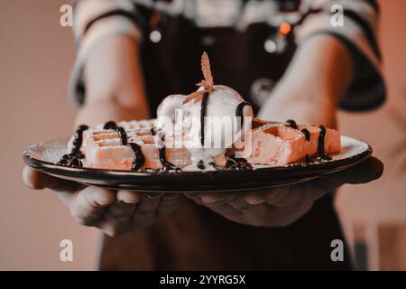 pantone-Ton. Mädchen, das die Waffel in den Händen hält. Serviert mit Eis. Köstliches Dessert zum Tee. Kochprozess. Dessert. Belgische Waffeln Stockfoto