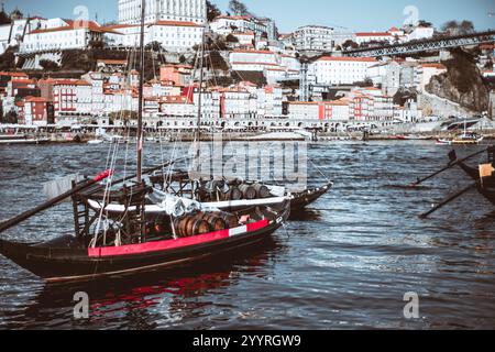 Traditionelles portugiesisches Rabelo-Boot mit Holzfässern, dockt am Fluss Douro in Porto, Portugal, mit farbenfroher Ribeira-Uferpromenade Stockfoto