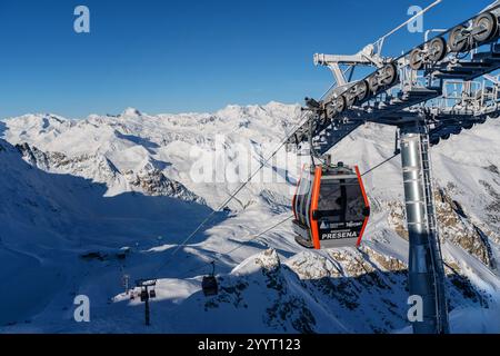 Ponte di Legno, Italien - 03.12.2023: Seilbahn gleitet am hellen Wintertag über schneebedeckte Berggipfel Stockfoto