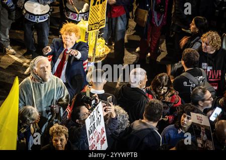 Tel Aviv, Israel. Dezember 2024. Während eines Protestes in Tel Aviv werden Demonstranten mit einer Maske des designierten US-Präsidenten Donald Trump und des israelischen Premierministers Benjamin Netanjahu gesehen. Am Samstag gingen Tausende auf die Straßen Israels und forderten die derzeitige Regierung unter Premierminister Benjamin Netanjahu auf, einen Geiselvertrag mit der Hamas zu schließen. (Foto von Eyal Warshavsky/SOPA Images/SIPA USA) Credit: SIPA USA/Alamy Live News Stockfoto