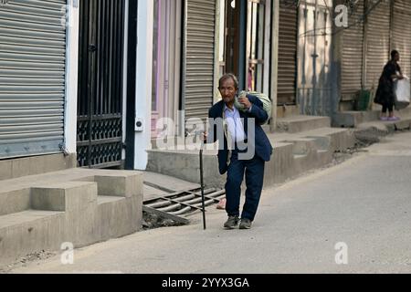 Ein älterer nepalesischer Mann, der in einem warmen Herbst in Thamel, Kathmandu, Nepal, eine Straße entlang läuft. Stockfoto