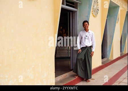 Der Reiseleiter steht in traditioneller Kleidung in einer Tür und posiert im Manuha-Tempel in Bagan, Myanmar Birma Stockfoto