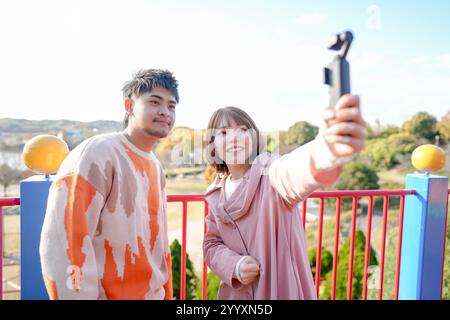 In einem großen Park in Handa City, Präfektur Aichi, spielt ein Paar im Alter von 20 Jahren auf dem Spielplatz und nimmt Selfies mit einem sm Stockfoto
