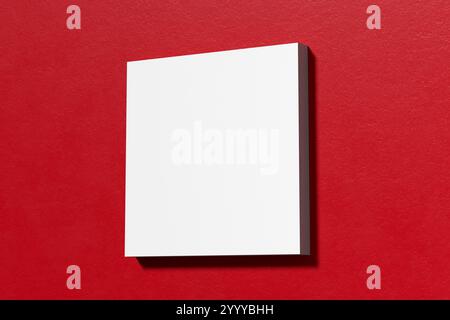 Minimalistische Komposition mit einer leeren weißen quadratischen Leinwand an einer roten Wand, ideal für die Präsentation von Kunstwerken oder Designs. 3D-Rendering. Stockfoto