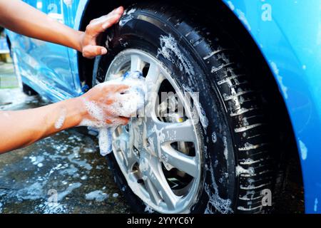 Reinigen Sie die Autoräder mit einem Mikrofasertuch, während Sie das Auto waschen Stockfoto