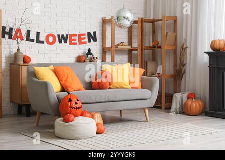 Das Innere des stilvollen Wohnzimmers mit Sofa, Kürbissen und Discokugel ist für Halloween-Party dekoriert Stockfoto