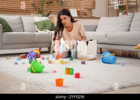 Müde, junge Mutter, die zu Hause Spielzeug in die Tasche steckt. Spannungskonzept Stockfoto