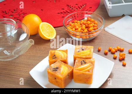 Tee aus gefrorenen Sanddornbriketts, Orangen und Gewürzen in der Teekanne in der Küche. Gesunde Ernährung und Jahreszeiten. Schnelle Getränke zum Zubereiten. Stockfoto