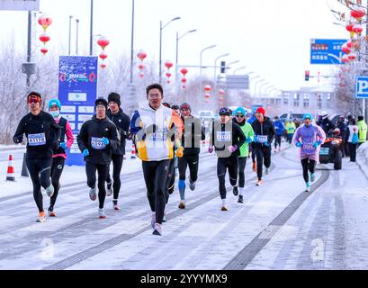 Urumqi, China, 22. Dezember 2024. Der Halbmarathon von Urumqi beginnt am 22. Dezember 2024 im Wintersport-Management-Center von Xinjiang in Urumqi, der Hauptstadt der Autonomen Region Xinjiang Uygur. Rund 6.000 Läufer nahmen an der Veranstaltung Teil. Quelle: Liu Xin/China News Service/Alamy Live News Stockfoto