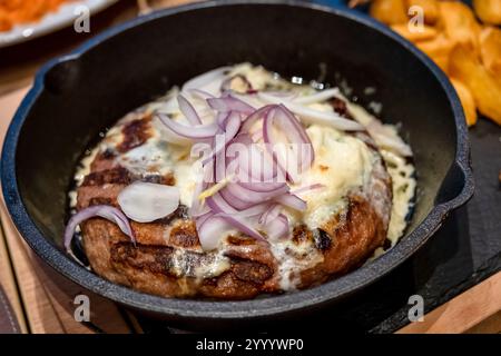 Zwiebelburger. Fleischburger mit gemahlenem Fleisch in Öl in einer Pfanne mit drei Zwiebeln gebraten, Nahaufnahme Stockfoto