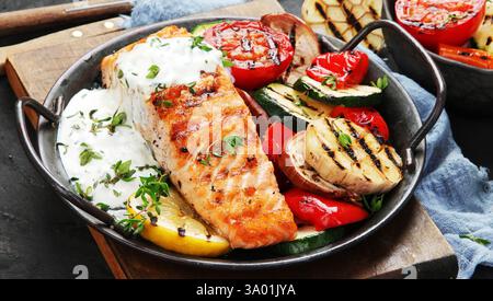 Lachssteak mit Gemüse und weißer Sauce frisch gegrillt. Gesundes Abendessen. Mediterrane Ernährung. Kopierbereich Stockfoto