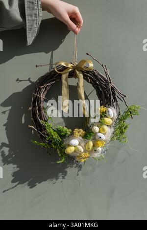 Nicht erkennbare Frau mit offenem Osterkranz-Dekor. Handgefertigtes kreatives Geschenk oder Geschenkidee. Keine Verschwendung umweltfreundliche Frühlings-Urlaubsdekoration. Stockfoto