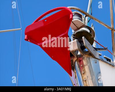 Ein hellroter Anker ist sicher an der Seite eines Segelbootes befestigt Stockfoto