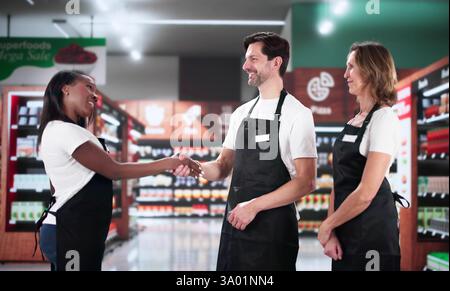 Ein vielfältiges Team von zufriedenen Mitarbeitern feiert erfolgreiche Supermarkt-Geschäftsvereinbarung. Stockfoto