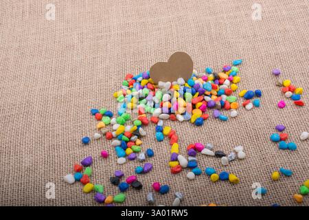 Herz aus Papier inmitten der bunten Steinchen auf Leinwand Boden Stockfoto
