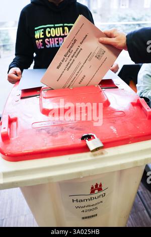 Hamburg, Deutschland. März 2025. Ein Wähler legt seinen Wahlzettel bei der Wahl der Hamburger Bundestagswahl in eine Wahlurne im KulturKlinker Barmbek (ehemals Bürgerhaus Barmbek). Am Sonntag wird in Hamburg ein neues parlament gewählt. Quelle: Christian Charisius/dpa/Alamy Live News Stockfoto