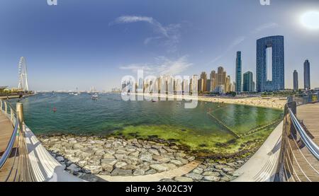 Dubai Marina mit Hochhäusern, einem Yachthafen und einer lebhaften Promenade tagsüber Stockfoto
