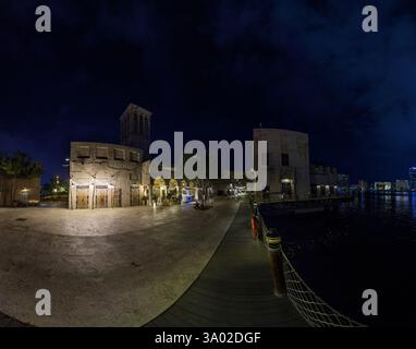Historischer Souk am Dubai Creek bei Nacht mit beleuchteten Gebäuden und Wasserreflexionen im Winter Stockfoto