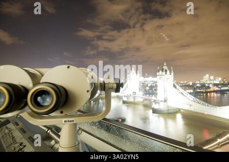 Tower Bridge, London bei Nacht, gesehen durch ein Nikon Fernglas. Beobachten Sie die beleuchtete Landmarke. Stockfoto
