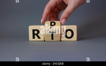 RPO vs. RTO-Symbol. Geschäftsmann-Hand dreht Holzwürfel und ändert das Wort RTO in RPO. Schöner grauer Hintergrund. Geschäftskonzept. Kopierbereich Stockfoto