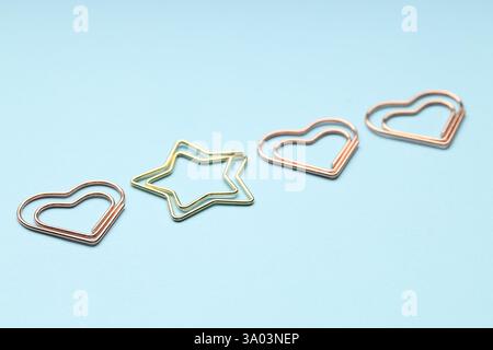 Verschiedene Büroklammern auf hellblauem Hintergrund, Nahaufnahme Stockfoto