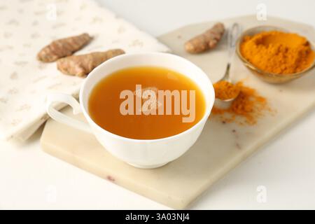 Aromatischer Kurkuma-Tee, Pulver und Rhizome auf weißem Tisch, Nahaufnahme Stockfoto