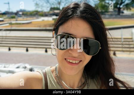 Die junge lateinfrau mit Sonnenbrille macht an einem sonnigen Tag ein Selfie Stockfoto