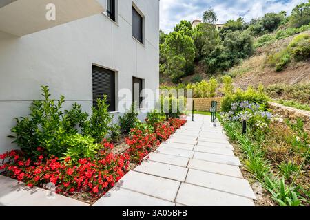 Ein Bild eines Gartens mit roten Blumen und Kaktuspflanzen im mediterranen Apartmentkomplex Stockfoto