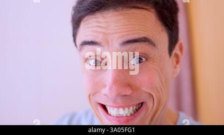 Mann macht komisches Gesicht mit breiten Augen und lächelnd Stockfoto